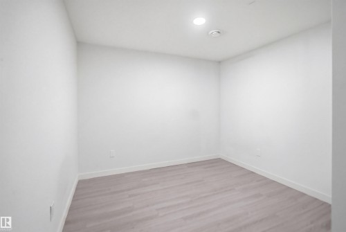 Neutral interior space featuring light wood-finish flooring, white walls, and a recessed ceiling light - 3545 11 Street, Edmonton, AB - Indoor Photo Showing Other Room