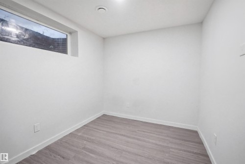 Neutral-toned flooring with a wood-finish pattern complements the white painted walls and baseboards - 3545 11 Street, Edmonton, AB - Indoor Photo Showing Other Room