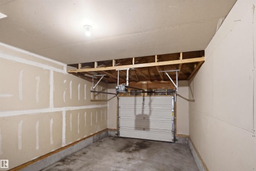 Single-bay garage featuring a concrete floor, exposed wood framing, and an overhead garage door opener - 3545 11 Street, Edmonton, AB - Indoor Photo Showing Garage