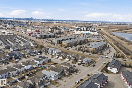 Aerial perspective showcasing a mixed-use development featuring residential properties, commercial establishments, and a distant city skyline - 3545 11 Street, Edmonton, AB - Outdoor With View