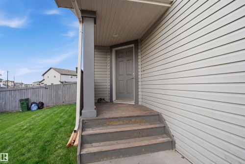 Rear exterior with light-colored horizontal siding, a covered entry, and a side-hinged door - 3545 11 Street, Edmonton, AB - Outdoor With Exterior