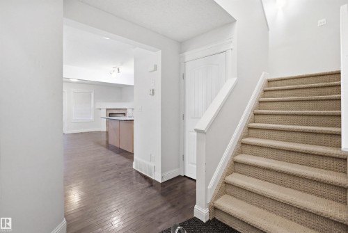Carpeted staircase with white balustrade, wood-finish flooring, and a white interior door - 3545 11 Street, Edmonton, AB - Indoor Photo Showing Other Room