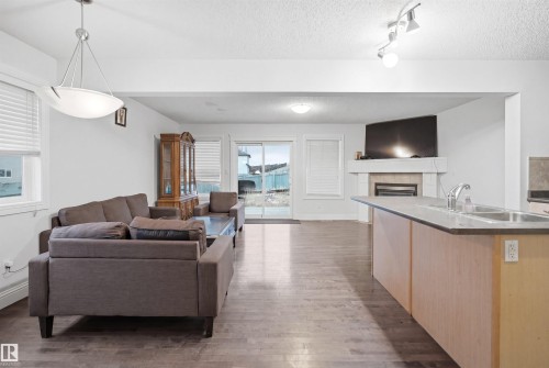Open-concept living area featuring wood-finish flooring, a built-in fireplace with a mantel, and sliding glass doors - 3545 11 Street, Edmonton, AB - Indoor With Fireplace