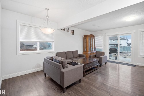 Spacious room featuring wood-finish flooring, white baseboards, and a contemporary ceiling light fixture - 3545 11 Street, Edmonton, AB - Indoor Photo Showing Living Room