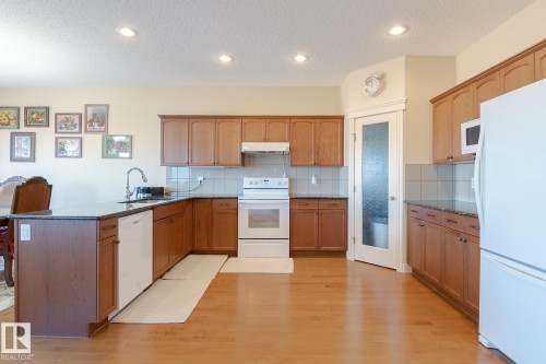 Kitchen featuring wood-finish flooring, recessed lighting, and a pantry with a frosted glass door - 7426 Getty Way, Edmonton, AB - Indoor Photo Showing Kitchen