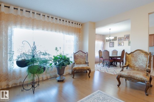 Spacious living area featuring wood-finish flooring and a wide window with sheer drapery - 7426 Getty Way, Edmonton, AB - Indoor Photo Showing Living Room