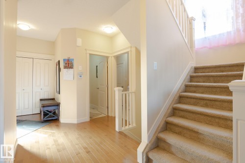 Entryway featuring light wood-finish flooring, a carpeted staircase with white railings, and multiple doors - 7426 Getty Way, Edmonton, AB - Indoor Photo Showing Other Room