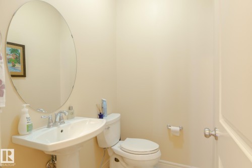 Pedestal sink with chrome faucet, complemented by a large oval mirror - 7426 Getty Way, Edmonton, AB - Indoor Photo Showing Bathroom