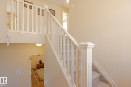 Staircase featuring white balusters and newel post, carpeted treads, and a neutral wall color - 7426 Getty Way, Edmonton, AB - Indoor Photo Showing Other Room