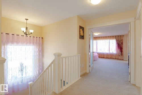 Carpeted hallway with white banister leading to an open doorway with frosted glass French doors - 7426 Getty Way, Edmonton, AB - Indoor Photo Showing Other Room