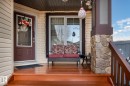 Welcoming front porch featuring a rich wood-finish deck and steps, a stone-clad pillar, and beige vinyl siding - 7426 Getty Way, Edmonton, AB  - Outdoor With Deck Patio Veranda With Exterior 