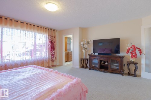 Carpeted room with a wide window, ceiling light fixture, and an open doorway revealing cabinetry - 7426 Getty Way, Edmonton, AB - Indoor Photo Showing Bedroom