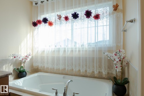 Built-in soaking tub featuring chrome fixtures set against a window with sheer and lace privacy coverings - 7426 Getty Way, Edmonton, AB - Indoor Photo Showing Bathroom