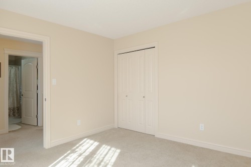 Neutral-toned bedroom featuring wall-to-wall carpeting and a bi-fold closet with panel detailing - 7426 Getty Way, Edmonton, AB - Indoor Photo Showing Other Room
