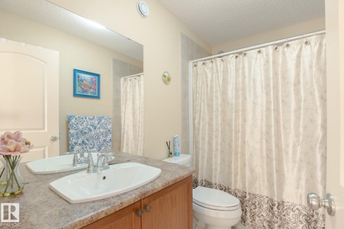 Bathroom featuring a single basin vanity with a laminate countertop, wood-finish cabinetry, and a full-width mirror - 7426 Getty Way, Edmonton, AB - Indoor Photo Showing Bathroom