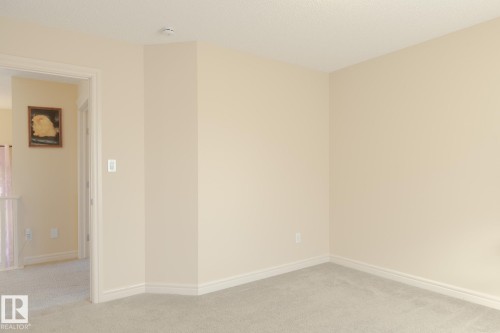 Wall-to-wall carpeting in a neutral tone, complemented by light beige wall paint and white trim - 7426 Getty Way, Edmonton, AB - Indoor Photo Showing Other Room