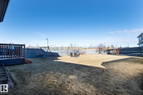 Spacious backyard featuring a large elevated wood deck, expansive lawn area, full perimeter fencing, and mature shrubbery - 7426 Getty Way, Edmonton, AB - Outdoor