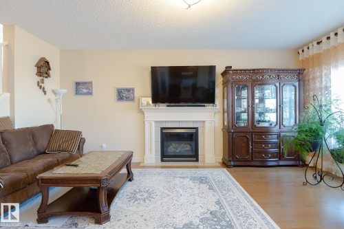 Living area featuring wood-finish flooring, a white mantel, and a recessed fireplace - 7426 Getty Way, Edmonton, AB - Indoor Photo Showing Living Room With Fireplace