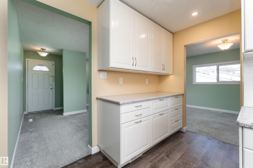 Kitchenette featuring white cabinetry, light-colored countertops, and wood-finish flooring - 13331 64 Street Nw, Edmonton, AB - Indoor Photo Showing Other Room