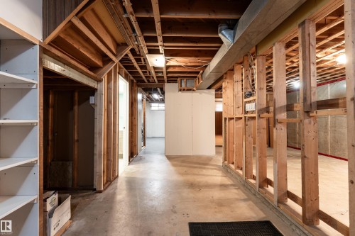 Unfinished basement featuring exposed wood framing, concrete flooring, visible ceiling joists, and white built-in shelving - 13331 64 Street Nw, Edmonton, AB - Indoor Photo Showing Basement