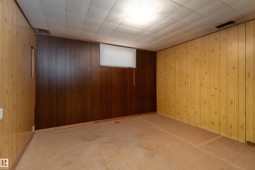 Expansive room featuring multi-toned wood-panel walls, a drop-tile ceiling with recessed lighting, and a small window with a roller shade - 13331 64 Street Nw, Edmonton, AB - Indoor Photo Showing Other Room