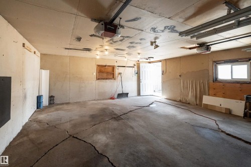 Concrete floor garage with exposed ceiling joists and two garage door openers - 13331 64 Street Nw, Edmonton, AB - Indoor Photo Showing Garage