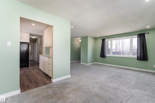 Spacious living area featuring light green walls, recessed lighting, and soft grey carpeting - 13331 64 Street Nw, Edmonton, AB - Indoor Photo Showing Other Room