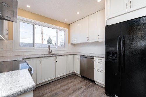 Kitchen featuring white cabinetry, gray speckled countertops, a subway tile backsplash, and wood-finish flooring - 13331 64 Street Nw, Edmonton, AB - Indoor Photo Showing Kitchen With Upgraded Kitchen