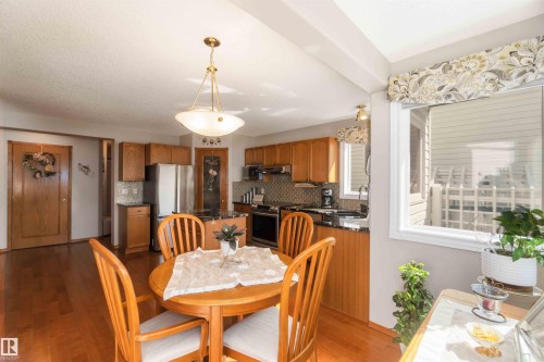 Open-concept kitchen and dining area featuring warm wood-finish flooring, a contemporary ceiling light fixture, granite countertops, and a tiled backsplash - 17224 83 Street, Edmonton, AB - Indoor Photo Showing Dining Room
