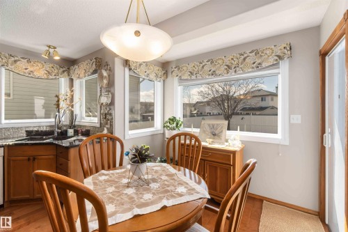 Dining area with a central pendant light fixture, wood-finish flooring, and multiple windows - 17224 83 Street, Edmonton, AB - Indoor Photo Showing Dining Room