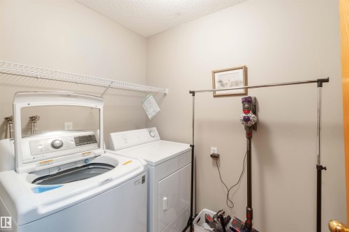 Laundry area featuring a top-load washing machine, a front-load dryer, and an overhead wire shelf - 17224 83 Street, Edmonton, AB - Indoor Photo Showing Laundry Room