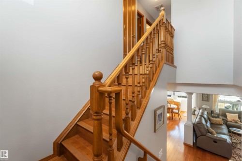Wood-finish staircase with turned newel posts and spindles, open to a lower living area featuring wood-finish flooring and a partial column - 17224 83 Street, Edmonton, AB - Indoor Photo Showing Other Room