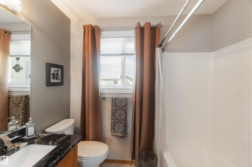 Bathroom featuring a dark-toned vanity with a built-in sink, a white toilet, and a white shower-tub combination - 17224 83 Street, Edmonton, AB - Indoor Photo Showing Bathroom