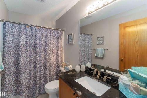 Bathroom featuring a dark stone countertop, integrated white sink, and brushed nickel faucet - 17224 83 Street, Edmonton, AB - Indoor Photo Showing Bathroom