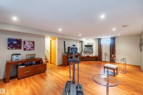 Spacious room featuring wood-finish flooring, recessed lighting, and a contemporary wall-mounted fireplace - 17224 83 Street, Edmonton, AB - Indoor