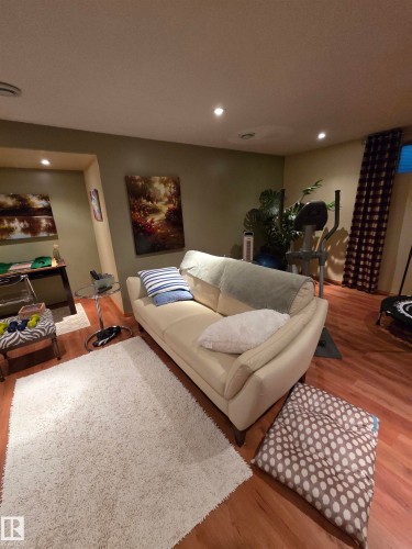Recessed ceiling lighting illuminates a spacious room featuring wood-finish flooring and a large area rug - 17224 83 Street, Edmonton, AB - Indoor