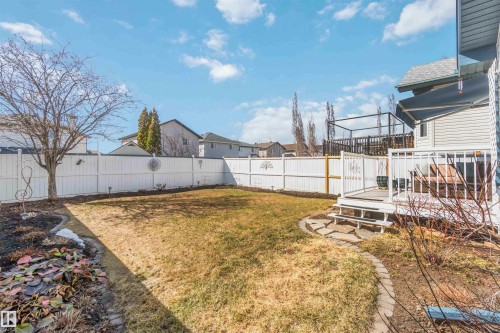 Fenced backyard featuring a wooden deck with railing, a stone pathway, and landscaped garden beds - 17224 83 Street, Edmonton, AB - Outdoor