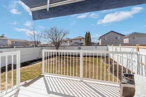 Expansive backyard featuring a white vinyl privacy fence, a wooden deck with white railings, and a dark blue retractable awning - 17224 83 Street, Edmonton, AB - Outdoor With Deck Patio Veranda