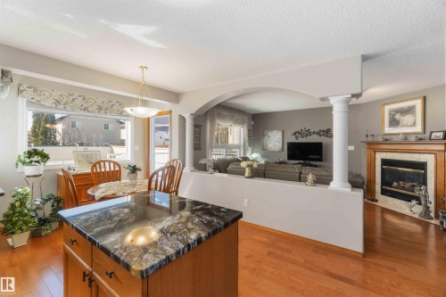 Kitchen island with a polished stone countertop and wood-finish cabinetry - 17224 83 Street, Edmonton, AB - Indoor Photo Showing Living Room With Fireplace
