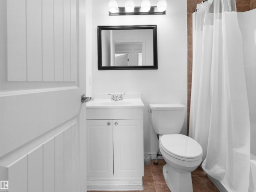 Bathroom featuring a white vanity with cabinet storage, a toilet, and a shower with a white curtain - #11 13215 153 Avenue, Edmonton, AB - Indoor Photo Showing Bathroom