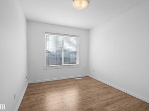 This room features light-toned hardwood flooring and crisp white walls, illuminated by a ceiling-mounted light fixture - #11 13215 153 Avenue, Edmonton, AB - Indoor Photo Showing Other Room