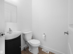 The bathroom features a modern vanity with a white basin and chrome faucet, a white toilet, and a wall-mounted mirror - 