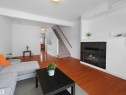 Living area featuring hardwood floors, a tiled fireplace, and a carpeted staircase with a wooden handrail - #11 13215 153 Avenue, Edmonton, AB  - Outdoor 