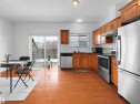 This kitchen features wood flooring, wooden cabinetry, and stainless steel appliances including a refrigerator, oven, and dishwasher - #11 13215 153 Avenue, Edmonton, AB  - Indoor Photo Showing Kitchen With Double Sink 