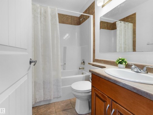 The bathroom features a vanity with a white sink, chrome faucet, and wood cabinetry - #11 13215 153 Avenue, Edmonton, AB - Indoor Photo Showing Bathroom