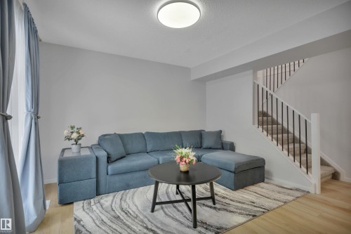 Living area featuring light colored flooring and walls, a staircase with black spindles, and a ceiling light fixture - 585 Knottwood Road W, Edmonton, AB - Indoor Photo Showing Living Room