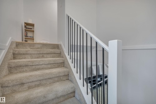 Staircase featuring light-colored carpeting, white handrails, and dark vertical balusters - 585 Knottwood Road W, Edmonton, AB - Indoor Photo Showing Other Room