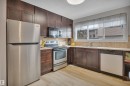 Kitchen featuring dark wood cabinetry, a stainless steel refrigerator, an oven with a stovetop, and a dishwasher - 585 Knottwood Road W, Edmonton, AB  - Indoor Photo Showing Kitchen 