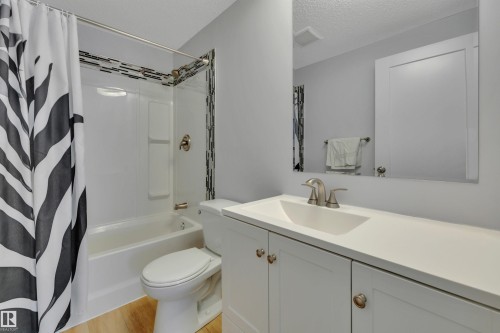 Full bathroom with a white vanity featuring a single sink and brushed nickel faucet, a mirror, and a bathtub with a shower - 585 Knottwood Road W, Edmonton, AB - Indoor Photo Showing Bathroom