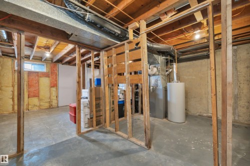 The property features an unfinished basement with exposed wooden beams, a water heater, and a small window for natural light - 585 Knottwood Road W, Edmonton, AB - Indoor Photo Showing Basement